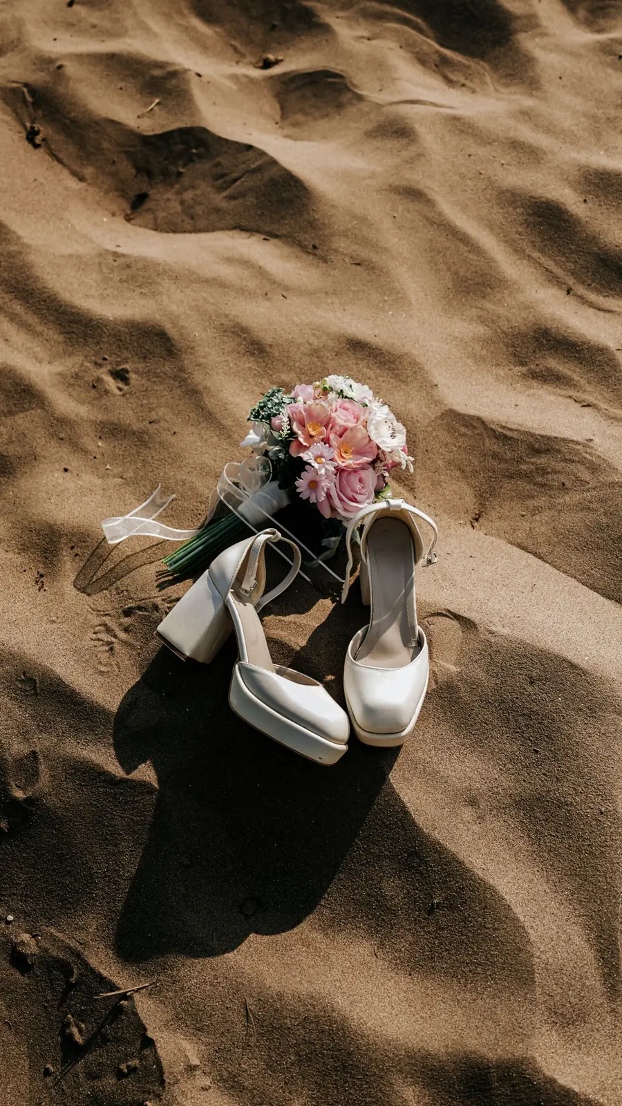 Zapatos de novia y ramo en la arena
